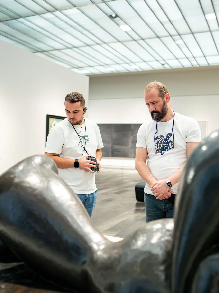 Two visitors pausing together to study a sculpture inside an art gallery.